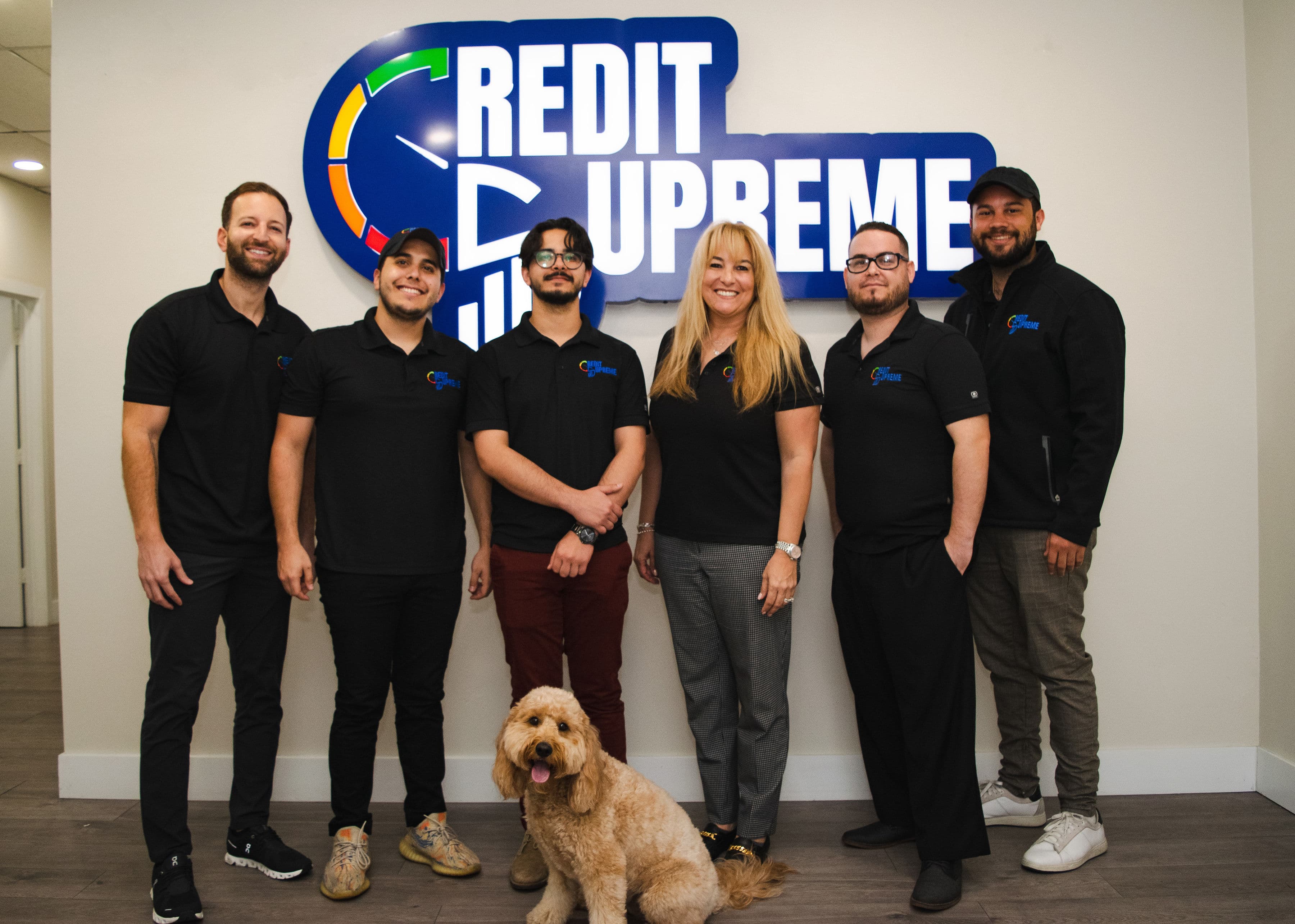 The Credit Supreme team standing in front of the Credit Supreme sign in the Miami office